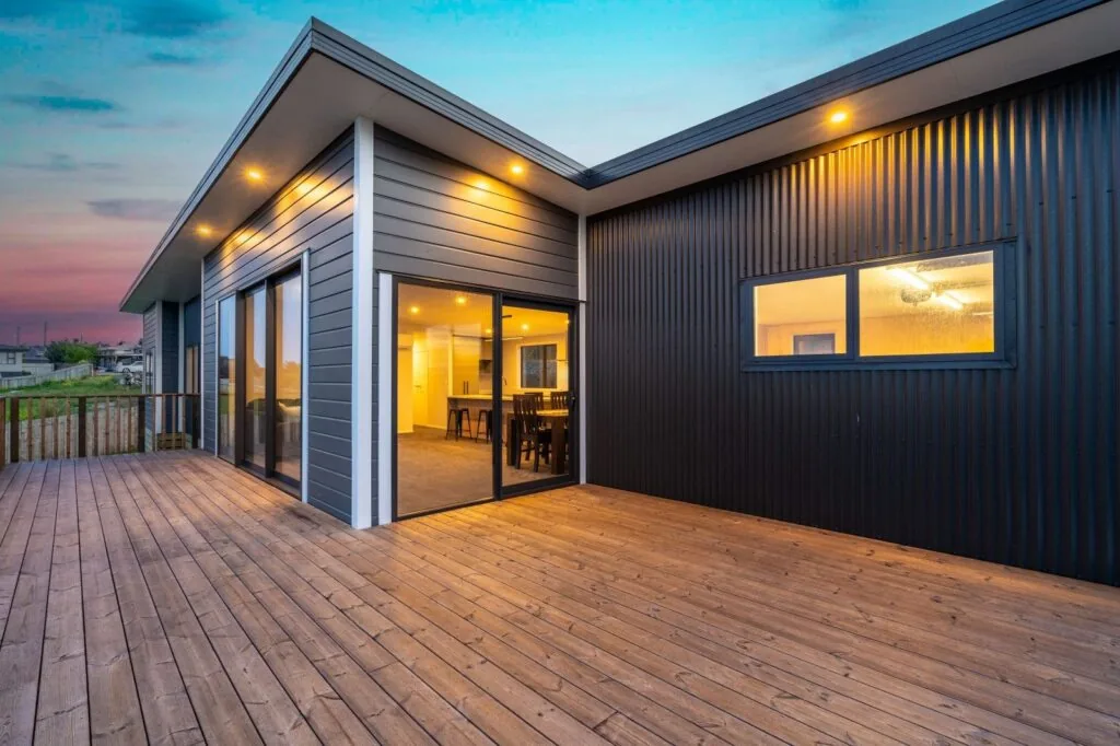 Completed Honiss Developments home with exterior deck and warm interior lighting
